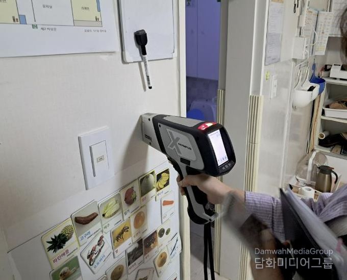 구청 관계자가 어린이집 실내 벽에 사용된 도료의 중금속 함량을 측정하고 있다