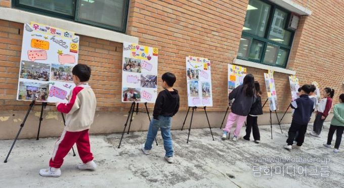 덕신초 학생들이 교내에 전시된 '우리들의 행복한 순간' 사진을 관람하고 있다.