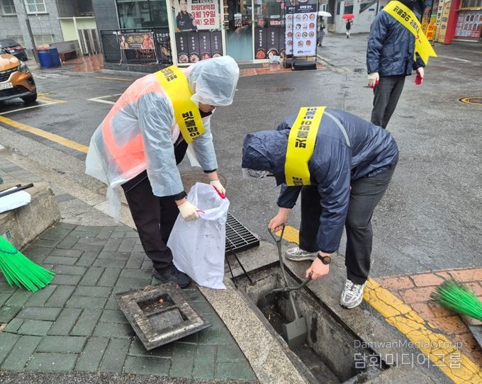 원들이 빗물받이에 쌓인 이물질 제거 작업을 하고 있다