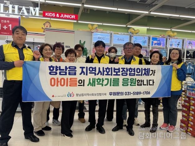 향남읍지역사회보장협의체 위원들이 ‘새 학기 봄맞이 바우처’ 지원사업 현수막을 들고 기념촬영을 하고 있다