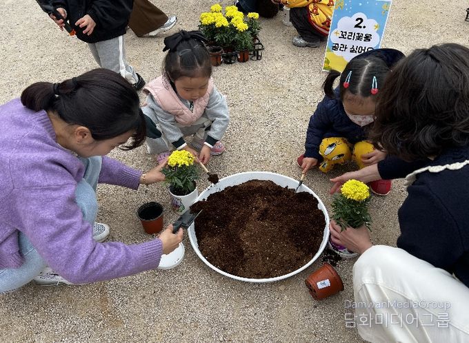강동유치원 3세반 유아들과 학부모들이 14일 '보호자 참여 수업'의 하나로 꼬리꽃을 심고 있다.